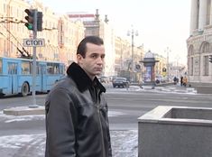 a man standing in the middle of a street next to a traffic light and buildings