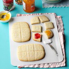 there are crackers and jams on the cutting board