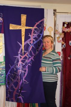 a woman standing in front of a cross on a purple banner with streamers hanging from it