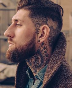 a man with a tattoo on his neck and ear is looking off to the side