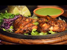 a plate filled with chicken and lettuce next to a bowl of green sauce