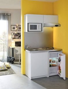 a small kitchen with yellow walls and white cupboards, including an open refrigerator freezer