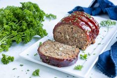 meatloaf with ketchup on a white plate next to some parsley