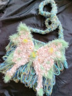 a handmade purse with feathers and beads on the front, sitting on a black background