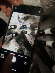 someone is taking a photo of their shoes on the bathroom floor with his cell phone