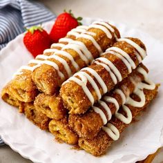 there are four desserts on the plate with white icing and strawberries in the background