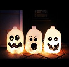 three lighted bottles with faces and mouths on them