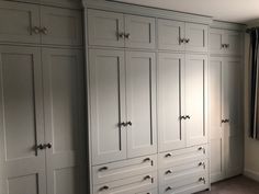 an empty room with white cabinets and carpeted flooring in front of a window