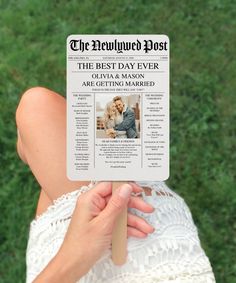 a person holding up a newspaper on top of their head in front of green grass