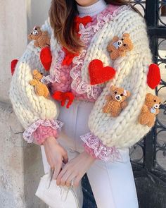 a woman is wearing a sweater with teddy bears on it and holding a white purse