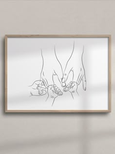 two hands touching each other in front of a white wall with a wooden frame on it