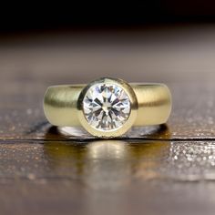 a yellow gold ring with a diamond on the top and bottom, sitting on a wooden surface