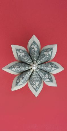 a dollar bill origami flower on a pink background