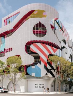 a large building with many colorful designs on it's face and windows, in the middle of a street