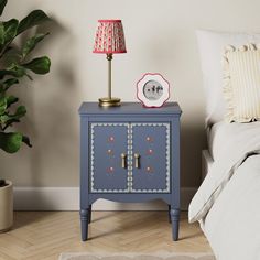 a small blue cabinet next to a bed with a red lamp on the end table