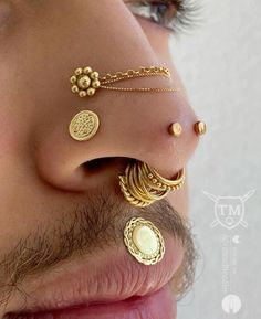 a close up of a person's nose with gold jewelry on it