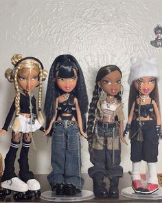 four dolls are lined up on a shelf