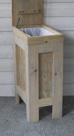 an old wooden box with a metal trash can in it's lid and the door open