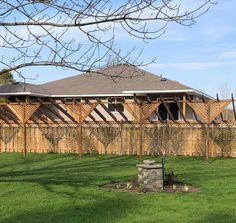 a wooden fence in front of a house with windows on the roof and grass around it