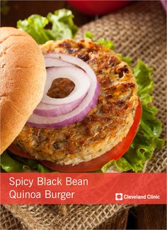 a close up of a burger on a bun with onions and lettuce next to it