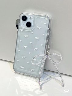 an iphone case with bows and hearts on it sitting next to a white wall,