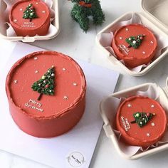 four red cakes decorated with christmas trees and decorations