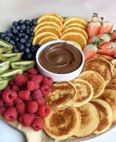 a platter with pancakes, fruit and chocolate sauce