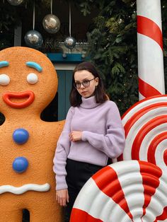 a woman standing next to a giant gingerbread man