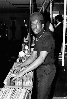 a man standing next to a stack of records