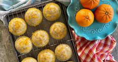 oranges and muffins on a cooling rack next to a blue plate with an orange