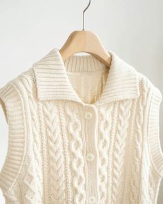 a white sweater hanging on a wooden hanger