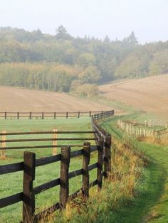 a wooden fence in the middle of a grassy field