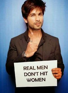 a man holding a sign that says real men don't hit women