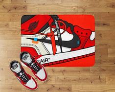 a pair of sneakers sitting on top of a wooden floor next to a red rug