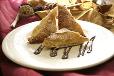 three pieces of pie on a white plate with chocolate drizzled around it