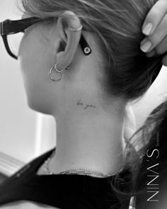 a woman with a tattoo on her neck and behind her ear is a pair of glasses