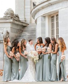 a group of women standing next to each other in front of a building with flowers