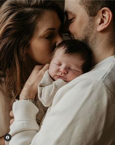 a man and woman holding a baby in their arms