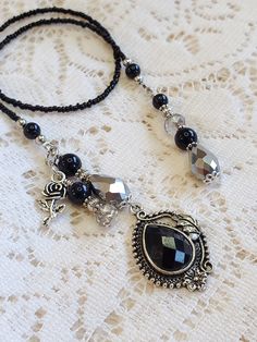 the necklace is adorned with black beads and silver accents on a white lace tablecloth