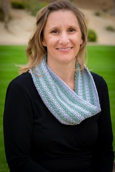 a woman wearing a blue and white knitted scarf in front of a green lawn