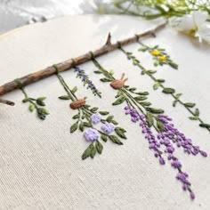 a close up of a cross stitch pattern on a piece of cloth with flowers and twigs