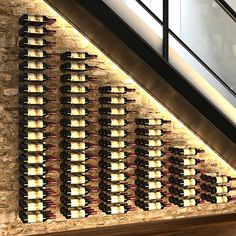 the wine bottles are lined up on the wall next to the stairs in the building