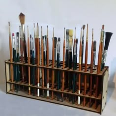 a wooden display case filled with lots of paintbrushes on top of a table