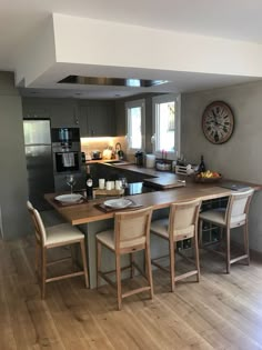 a kitchen with an island table and chairs in the center, along with a clock on the wall