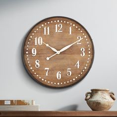 a large wooden clock on the wall next to a vase