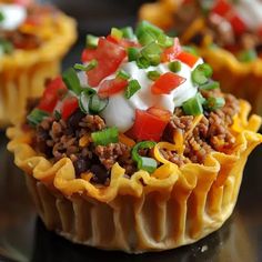 some taco cups are sitting on a black plate and have toppings in them