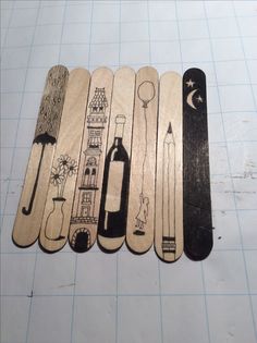 five wooden skis are lined up on a cutting board, with different designs and shapes