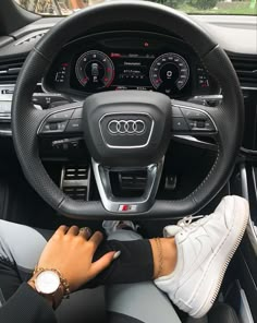 a person driving a car with their hands on the steering wheel and wearing white sneakers