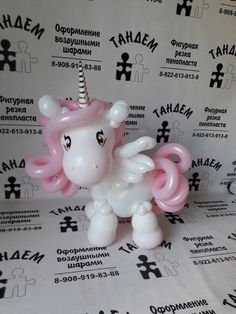 a pink and white pony with a horn on it's head sitting in front of a wall