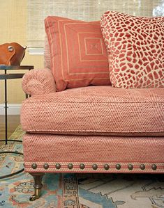 a living room with an orange couch and pillows on top of the couch, next to a lamp